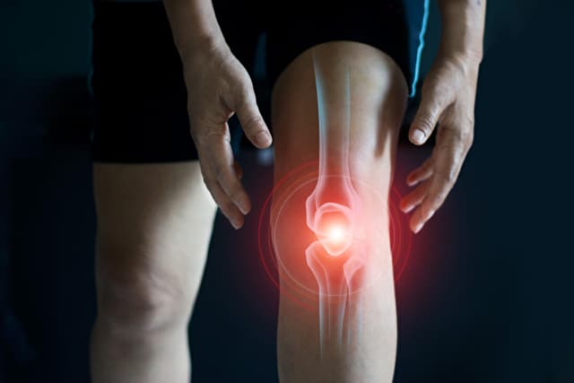 膝の痛みに苦しむ老女。暗い背景に腱の問題と関節の炎症。